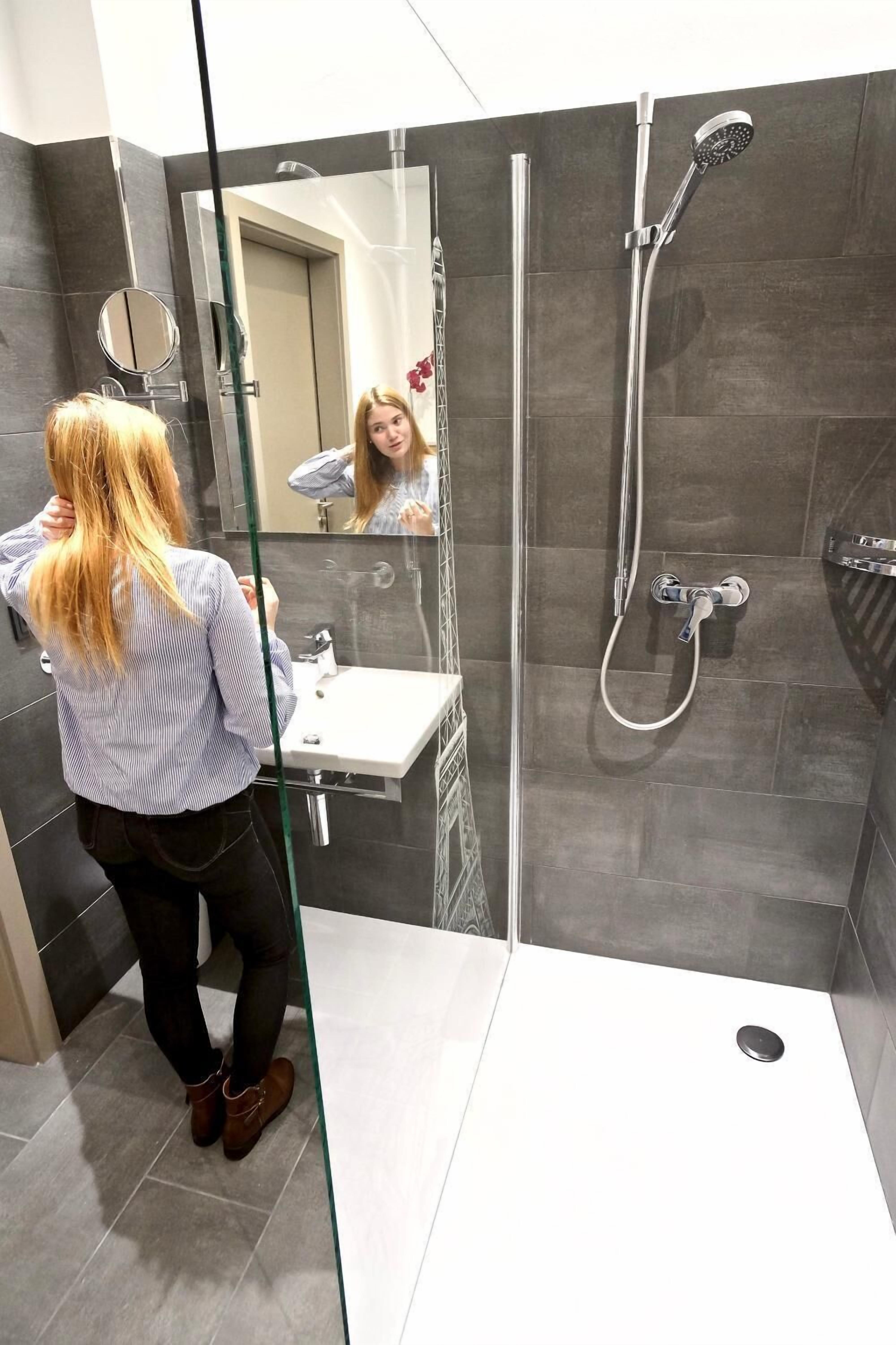 A modern bathroom with a glass shower enclosure, a standalone sink, and a mirror.