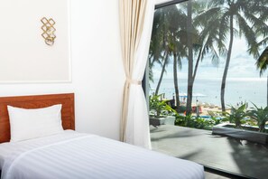 Une chambre avec un lit, vue sur la plage et des palmiers.