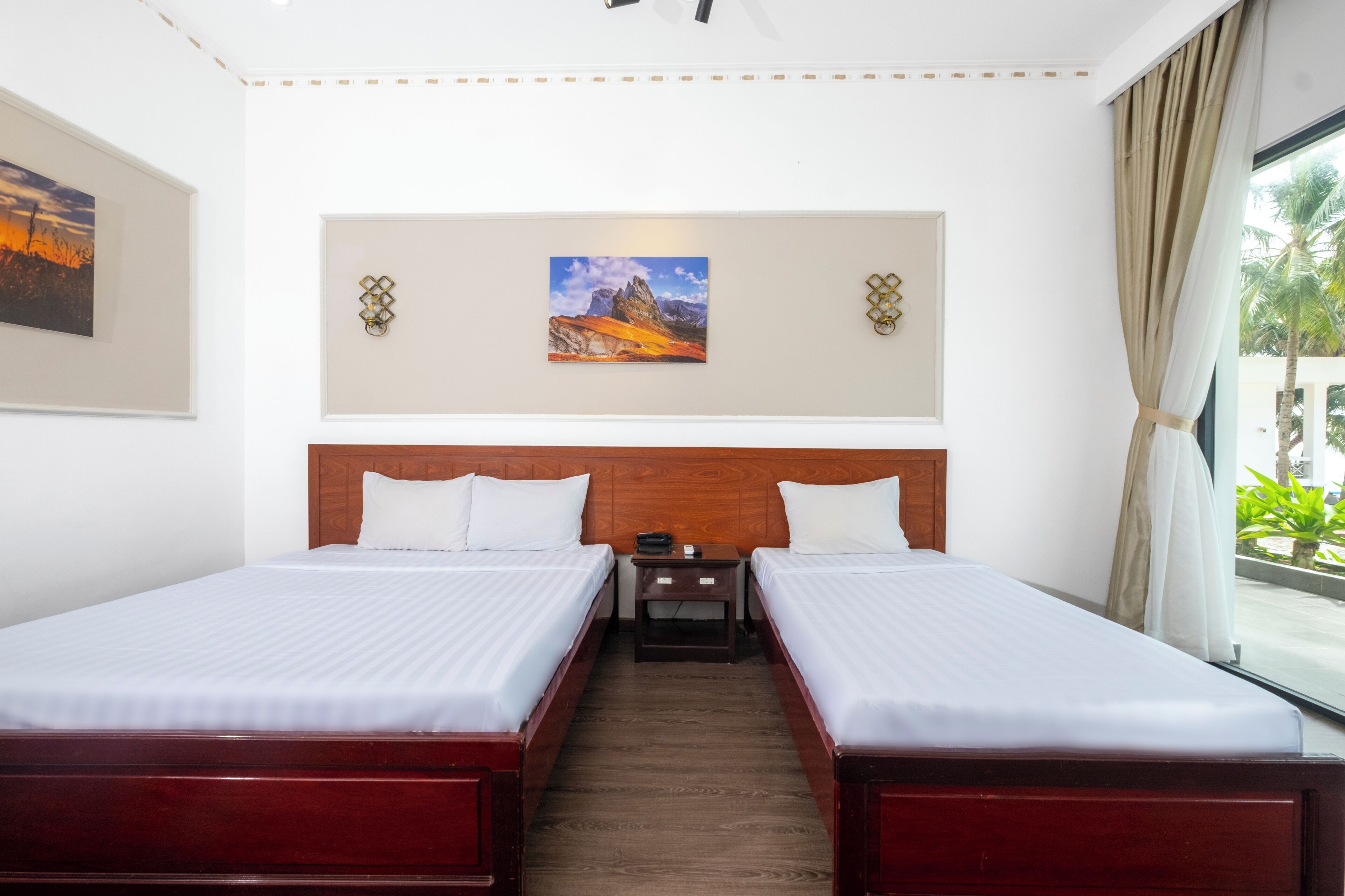 A hotel room with two beds, a wooden headboard, a nightstand, and a painting on the wall.