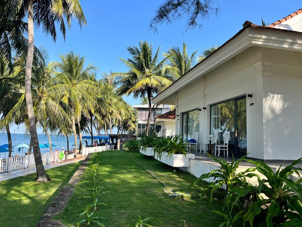 A beachfront property with a white building, palm trees, and a view of the sea. - Hawaii Resort Phu Quoc (Phu Quoc)