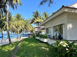 A beachfront property with a white building, palm trees, and a view of the sea.
