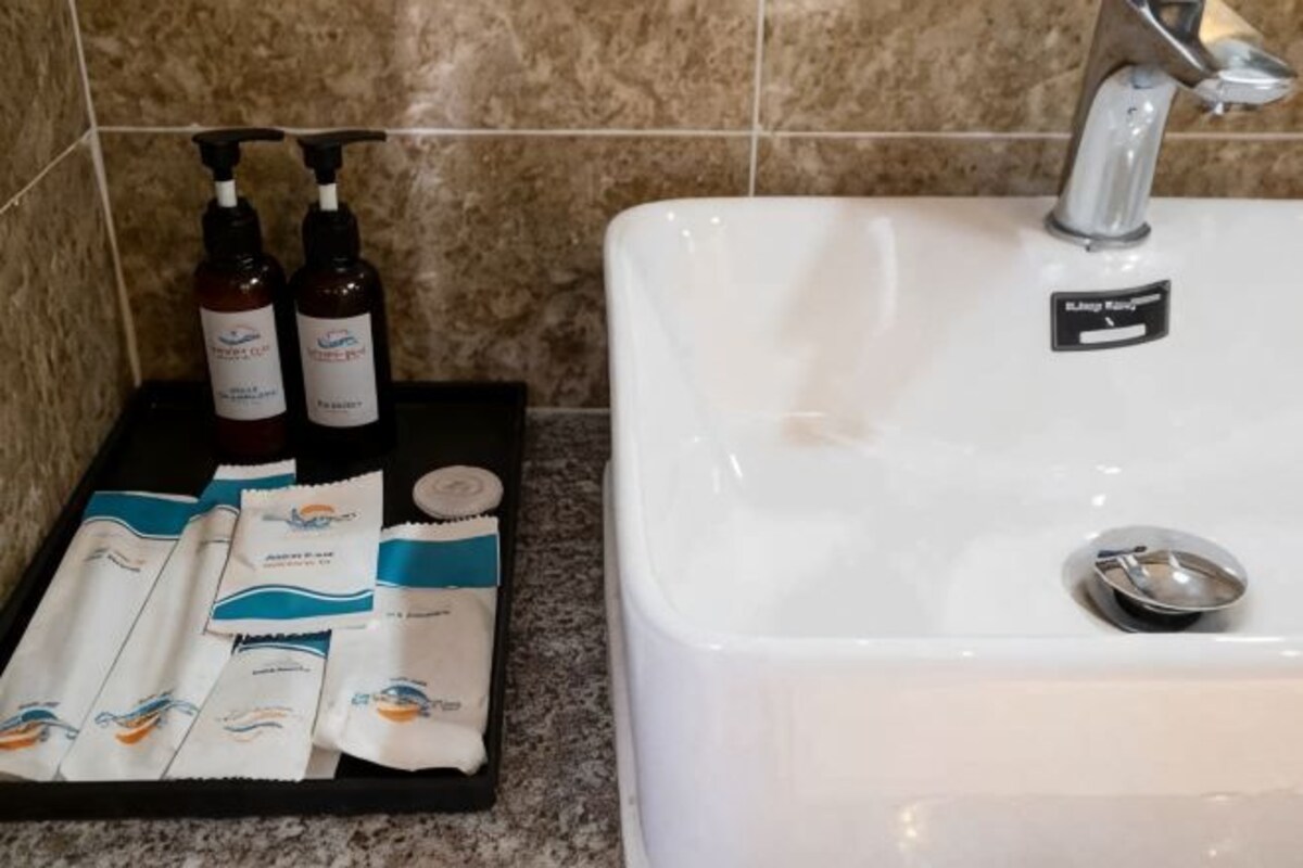 Une salle de bain avec un lavabo blanc, un plateau contenant des articles de toilette et un porte-serviettes.