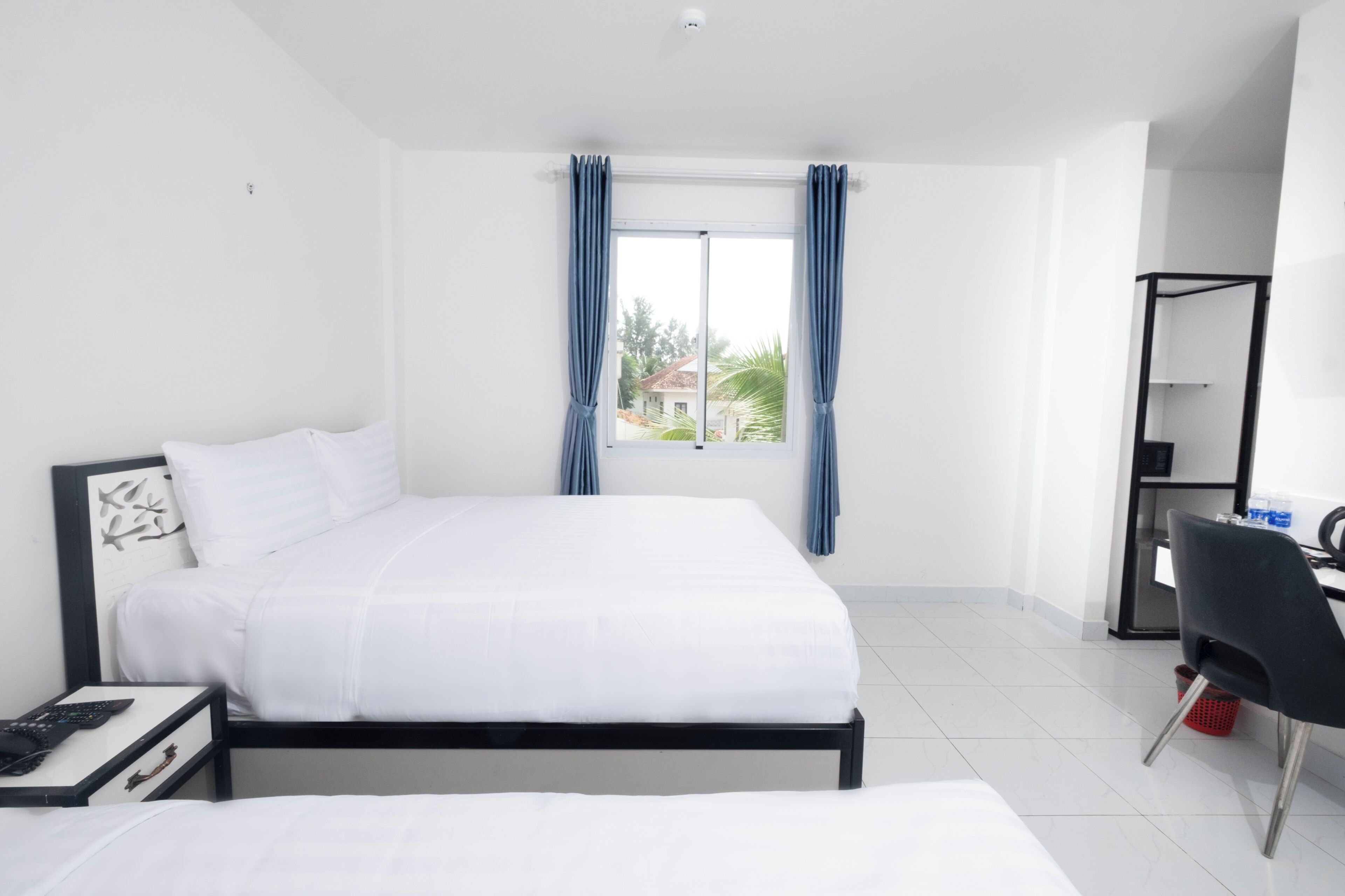 A hotel room with a bed, a desk, a chair, and a window with curtains.
