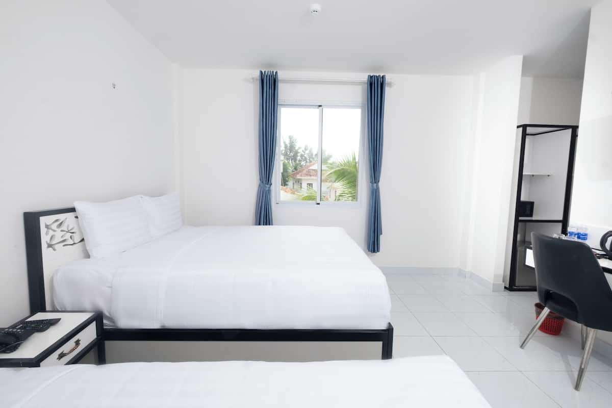 A hotel room with a bed, a desk, a chair, and a window with curtains.
