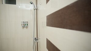 Ein Badezimmer mit Dusche, Handtuchhalter und Seifenspender.