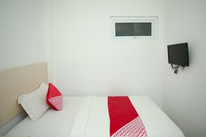 A hotel room with a bed, a window, a wall-mounted TV, and a red and white patterned throw blanket. - Hotel O Lapan Lapan (Banjarmasin)