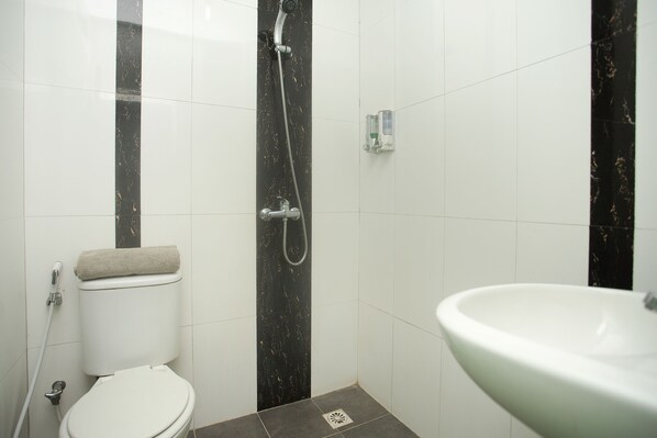 Et badeværelse med toilet, brusebad og håndvask.
