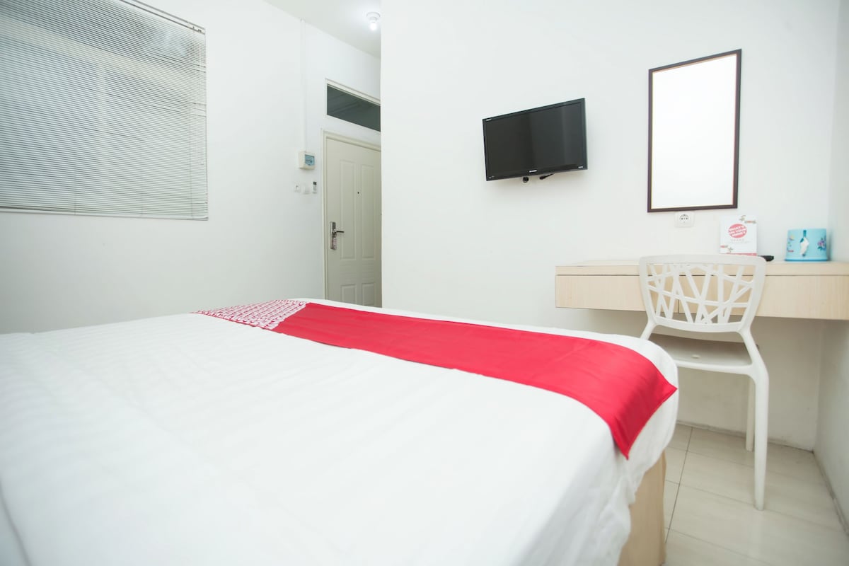 Une chambre à coucher avec un lit, un bureau, une chaise, une télévision et un miroir.