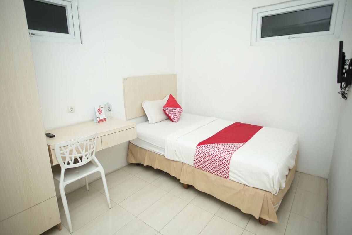 Une petite pièce propre, avec un lit, un bureau et une chaise.