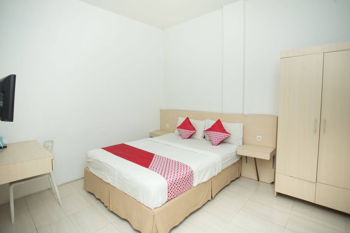 Une chambre à coucher comprenant un lit, une table de chevet, une armoire et un bureau.