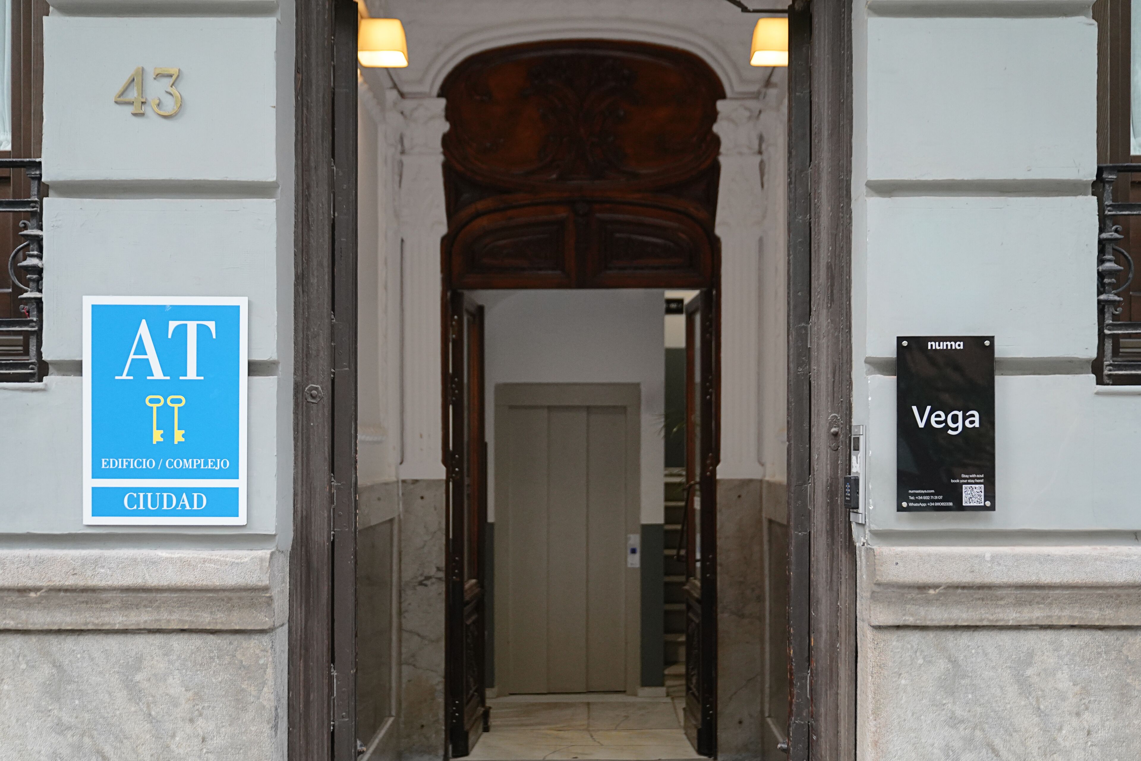 An entrance with a sign indicating 'AT Edificio/Complejo Ciudad' and another sign for 'Vega'.