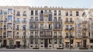 A row of multi-story buildings with balconies, a street in front, and a pedestrian crossing. - Numa Granada Vega (Granada)