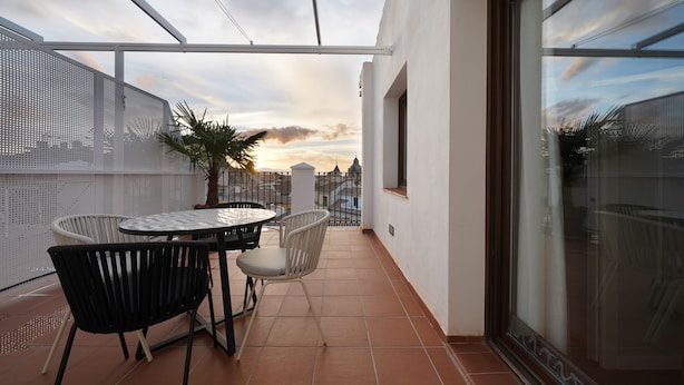 A balcony with a table and chairs, a potted plant, and a view of the cityscape. - Numa Granada Vega (Granada)