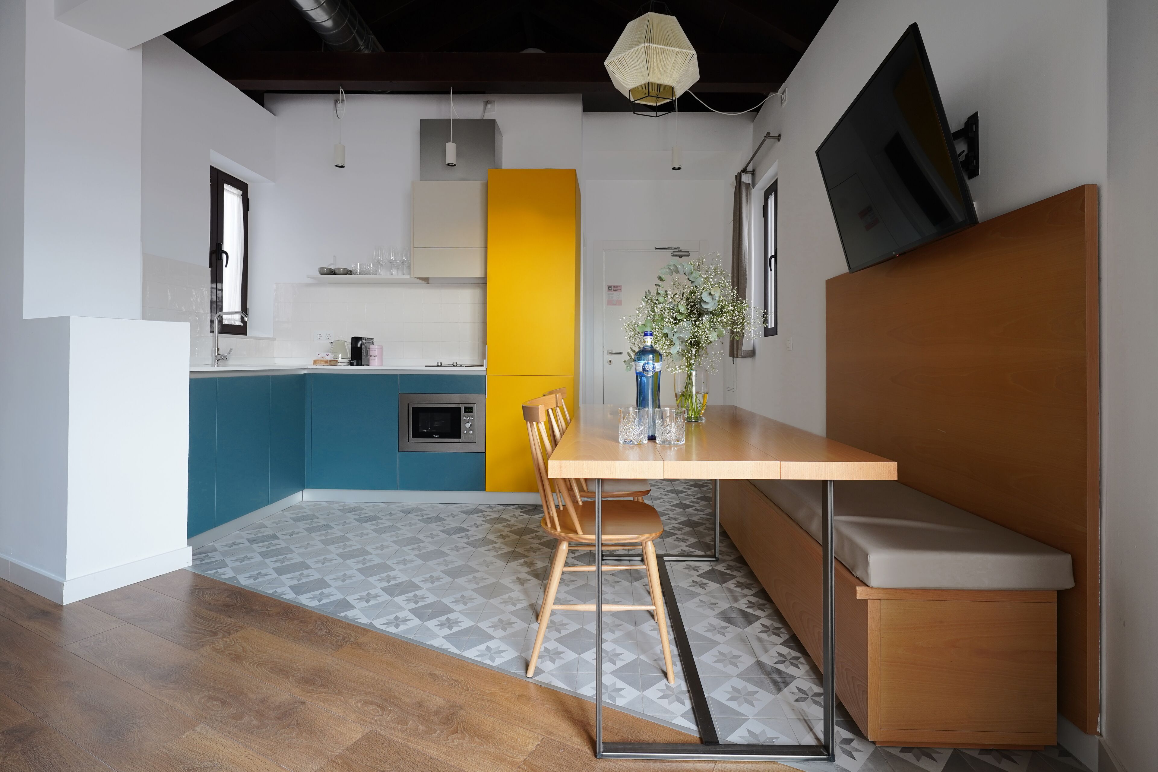 Una cocina moderna con comedor, que incluye una mesa de madera, sillas y un banco.