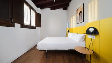 Un dormitorio con cama, mesita de noche, lámpara y ventana con cortinas.