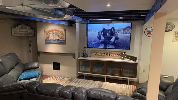 Un système de cinéma maison comprenant un grand téléviseur à écran plat, une enseigne publicitaire pour du whisky et une affiche ancienne accrochée au mur.