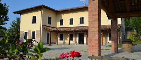 A two-story building with a courtyard, featuring a brick column and a wooden pergola.