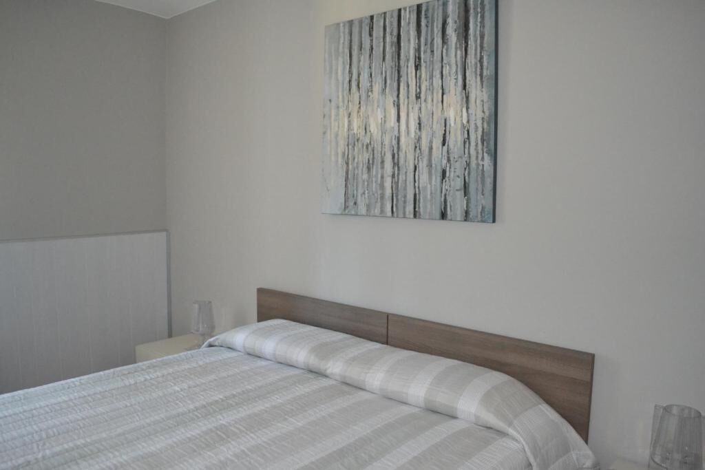A bedroom with a bed, a nightstand, and a wall-mounted artwork.