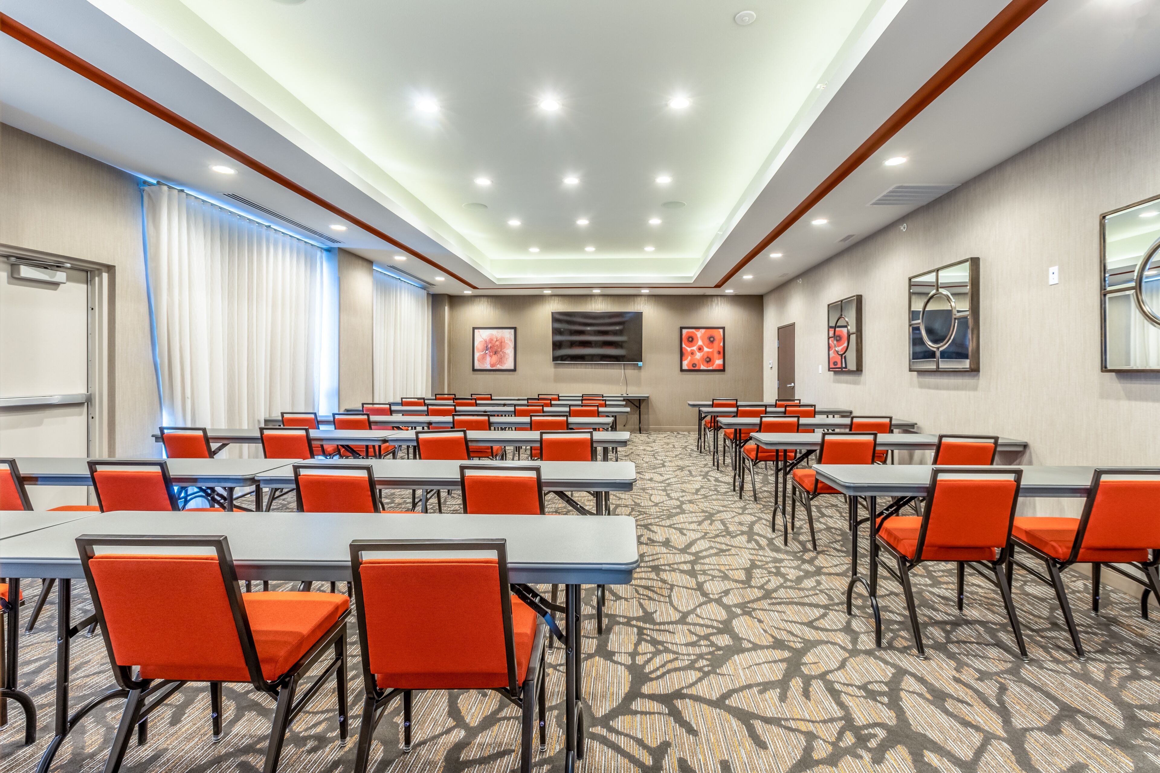 A conference room with tables and chairs, a patterned carpet, and a ceiling with recessed lighting.