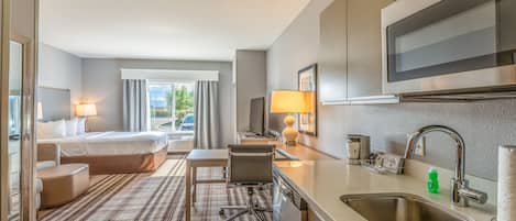 Une chambre d’hôtel équipée d’un lit, d’un bureau, d’une chaise, d’une télévision, d’un lavabo et d’une fenêtre avec des rideaux.