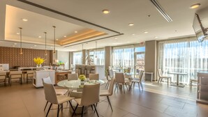 A spacious hotel lobby with a central round table, seating arrangements, and a kitchen area. - Hawthorn Extended Stay by Wyndham Loveland (Loveland)