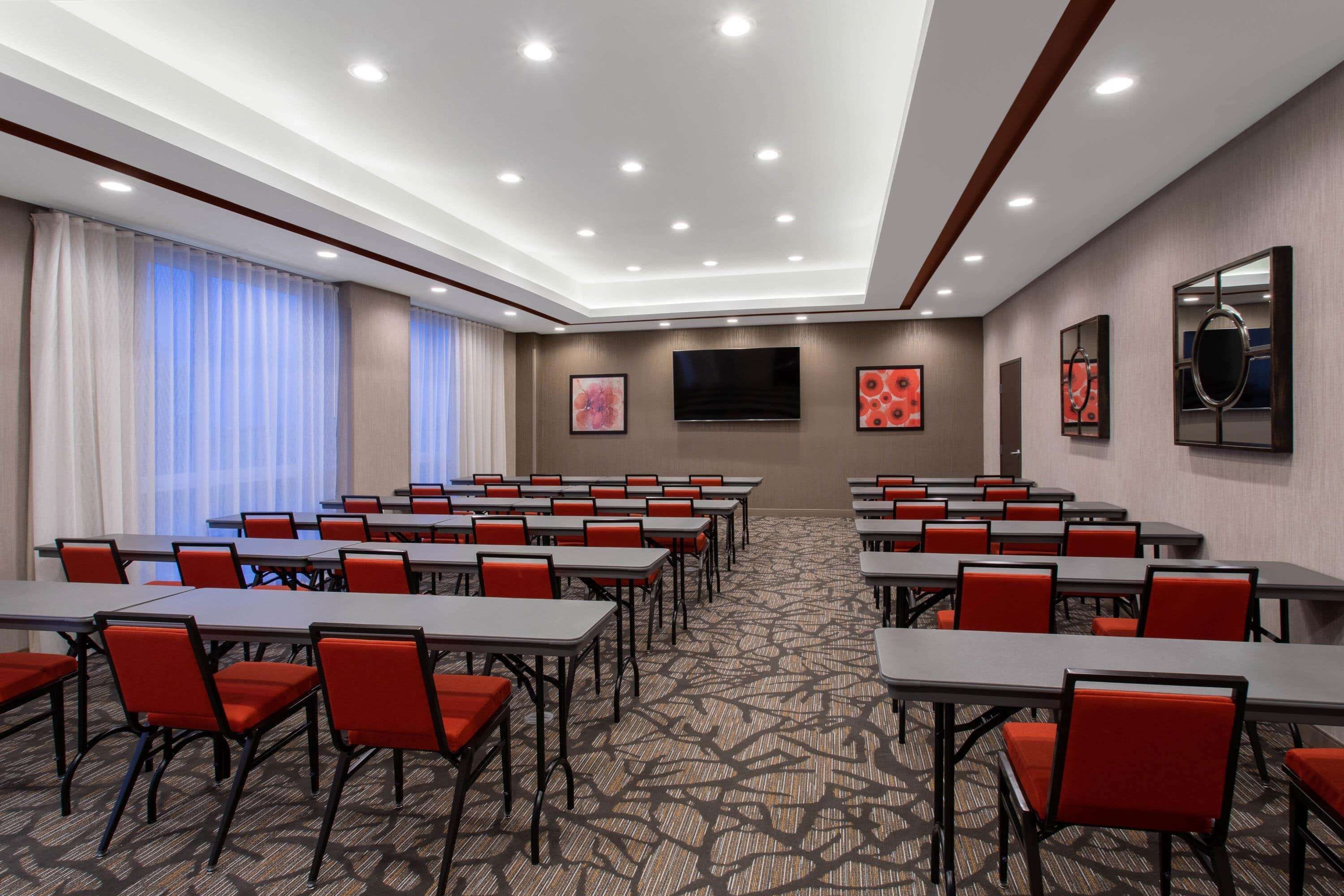 A conference room with tables and chairs, a flat-screen TV, and artwork on the walls.