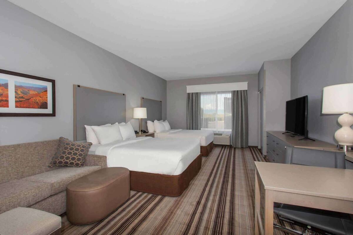 Een hotelkamer met een groot bed, een slaapbank, een televisie en een bureau.