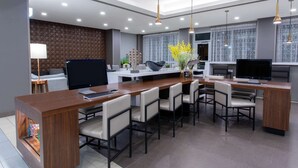 A modern office space with a long wooden desk, multiple chairs, a television, and a decorative plant. - Hawthorn Extended Stay by Wyndham Loveland (Loveland)