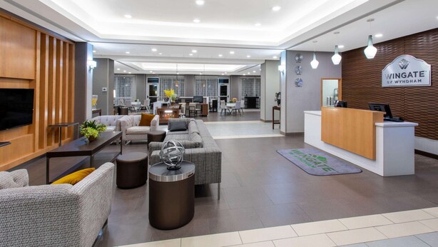 A modern hotel lobby with a reception desk, seating area, and a large flat-screen TV mounted on the wall. - Hawthorn Extended Stay by Wyndham Loveland (Loveland)