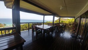 A covered outdoor deck with a table and chairs, overlooking the ocean. - Campismo Ninho 23 (Ponta d'Ouro)