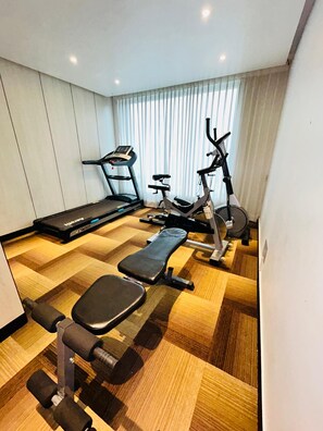 A gym with a treadmill, elliptical, bench press, and dumbbells. - Novanta Jamshedpur (Adityapur)