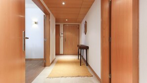 Un couloir avec des portes en bois, une petite table et un luminaire au plafond.