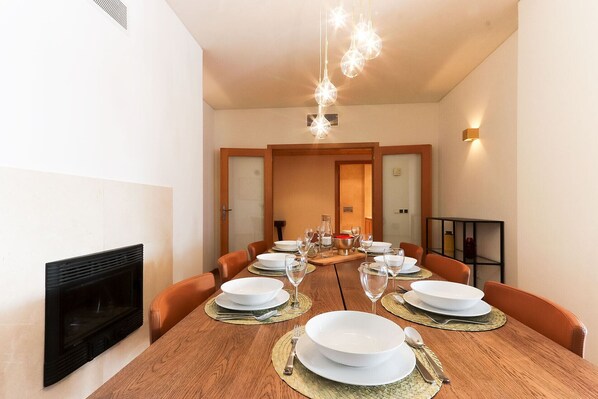 A dining room with a long wooden table set for a meal, surrounded by orange chairs. - Expo Prestige by Homing (Lisbon)