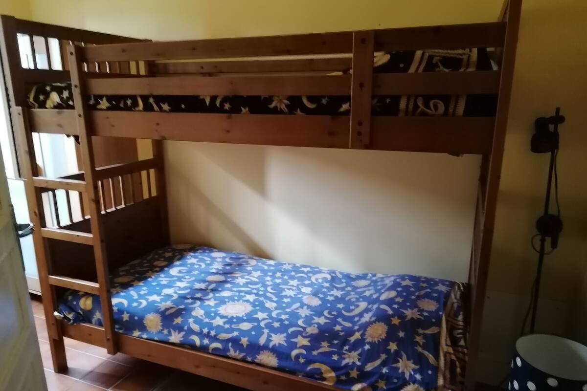 Ein Etagenbett mit blauer Bettdecke, verziert mit einem Stern- und Mondmuster.