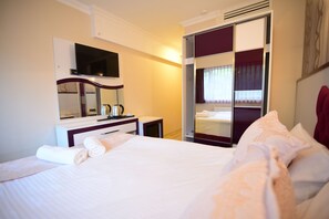 A hotel room with a bed, a desk with a flat-screen TV, a mirror, and a wardrobe with sliding doors. - Özdemir Palas Hotel (Ankara)