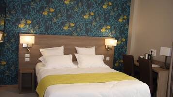 Een hotelkamer met een bed, twee nachtkastjes, een bureau en een stoel.