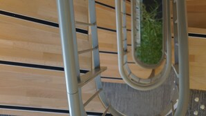 Una escalera de caracol con barandilla metálica y vistas a un techo de madera.