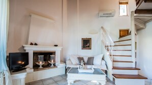 Ein Wohnzimmer mit Kamin, Fernseher, Treppe und Esstisch.