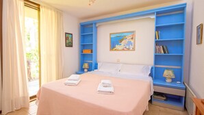 Ein Hotelzimmer mit Bett, Nachttisch, einer blauen Regaleinheit und einem Gemälde an der Wand.