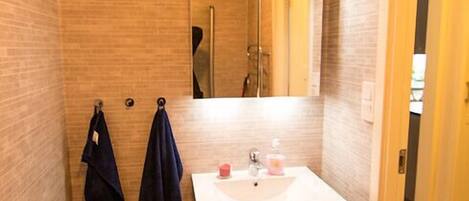 A compact bathroom with a white sink, mirror, and towel rack.