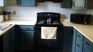 A kitchen with dark blue cabinets, a black stove, and a microwave.