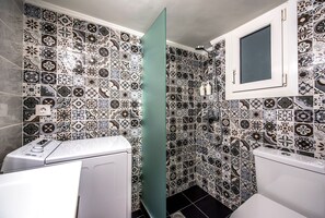 Une salle de bain avec des carreaux décorés, un lave-linge et des toilettes.