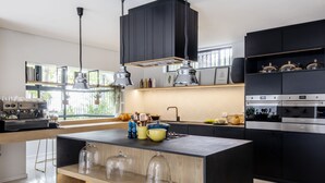A modern kitchen with a central island, black cabinets, stainless steel appliances, and pendant lighting. - Camissa House (Cape Town)