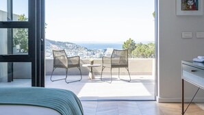 A bedroom with a large bed, a balcony with a view, and a small table with chairs. - Camissa House (Cape Town)