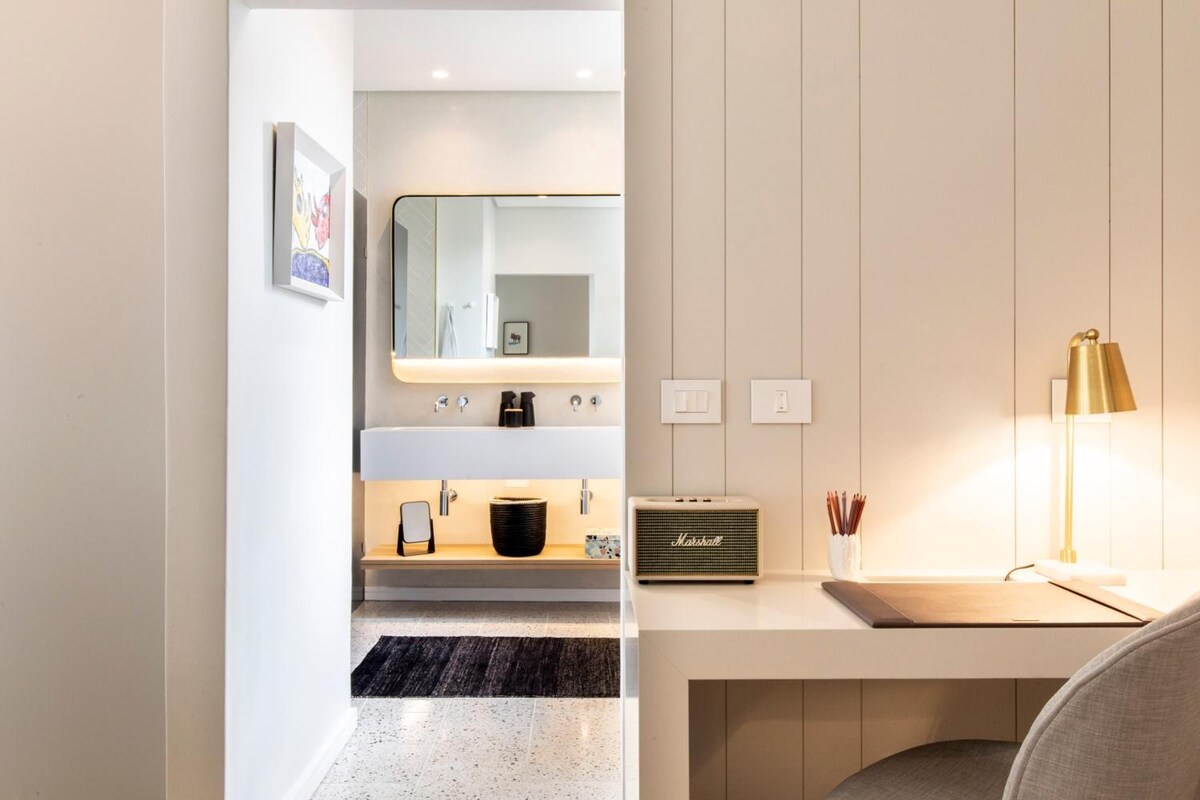 Une salle de bain moderne équipée d’un meuble-lavabo, d’un miroir, d’un évier et d’une radio.