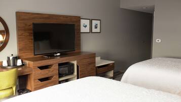 Une chambre d’hôtel équipée d’une télévision, de meubles en bois, d’un four à micro-ondes et de deux lits.