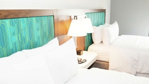 A hotel room with a bed, white bedding, a nightstand with a lamp, and a patterned headboard. - Hampton Inn & Suites Dundee (Dundee)