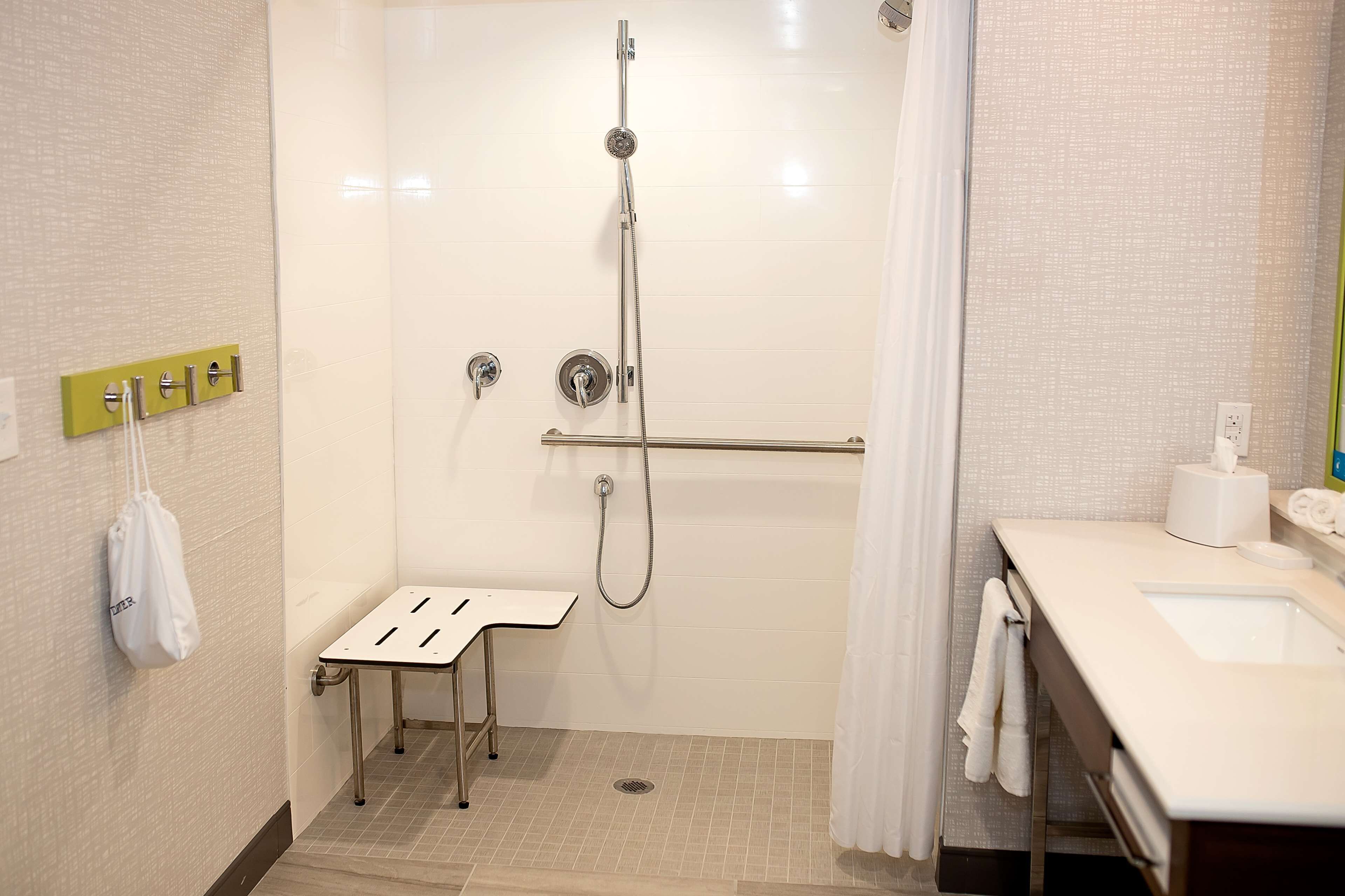 A modern bathroom with a walk-in shower, a small bench, a toilet, and a sink.