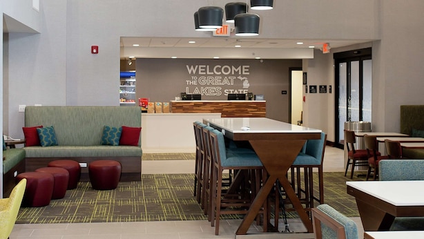 A modern hotel lobby with a reception desk, seating area, and a large chandelier. - Hampton Inn & Suites Dundee (Dundee)