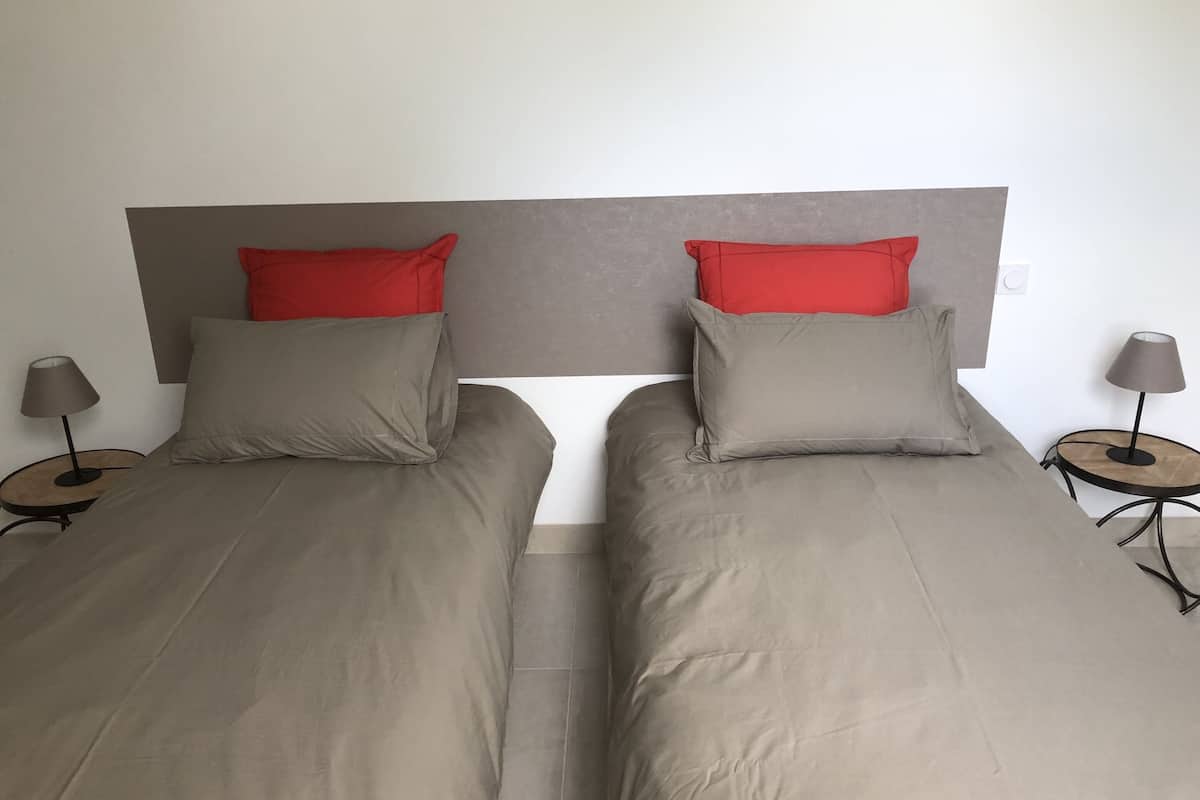 A double bed with two pillows, a headboard, and two bedside tables with lamps.